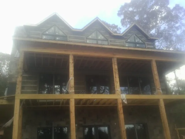 Dormers and porch framing on a large log home under construction — Roof Coating work by our crew in Boone
